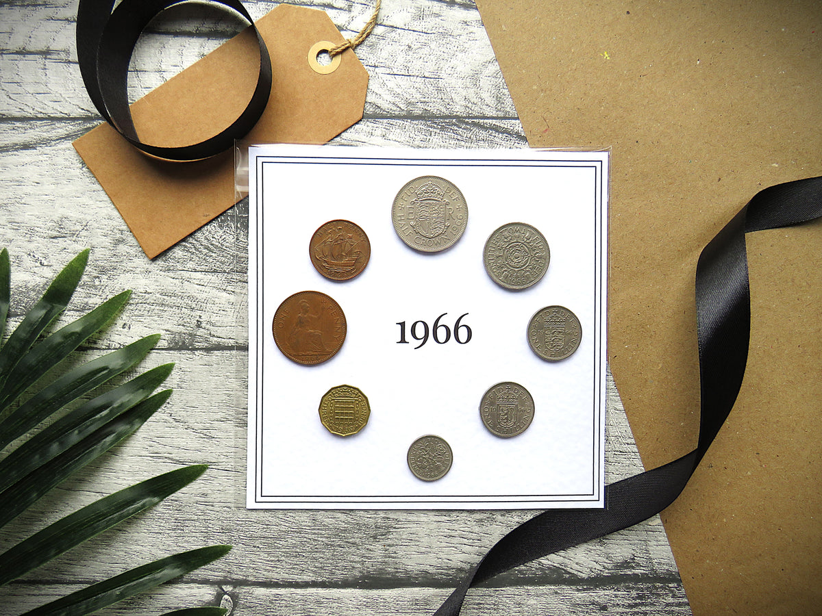 Collection of vintage coins from 1966 on a white card with ribbons and a tag on a wooden surface.