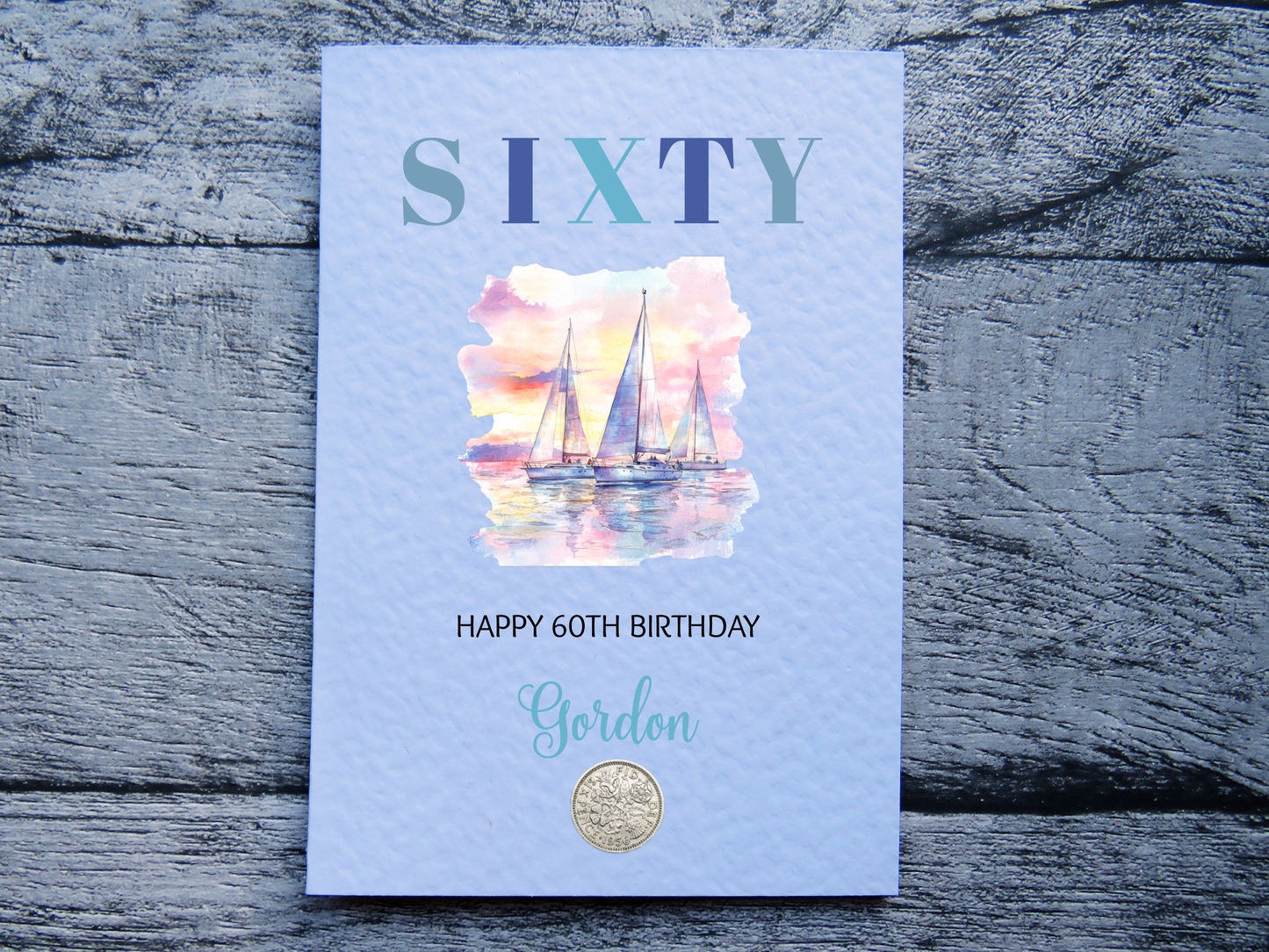 Sailing themed 60th birthday card with real 1966 sixpence, personalised with a name on a wooden surface