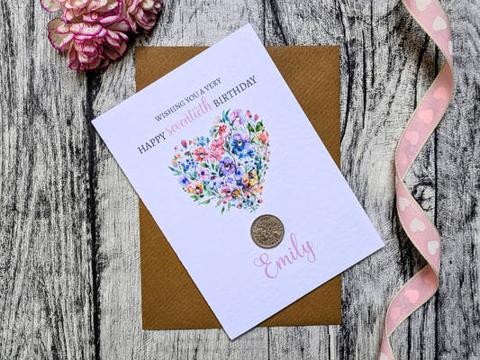 Greeting card with floral design and text on a wooden surface with a pink ribbon.